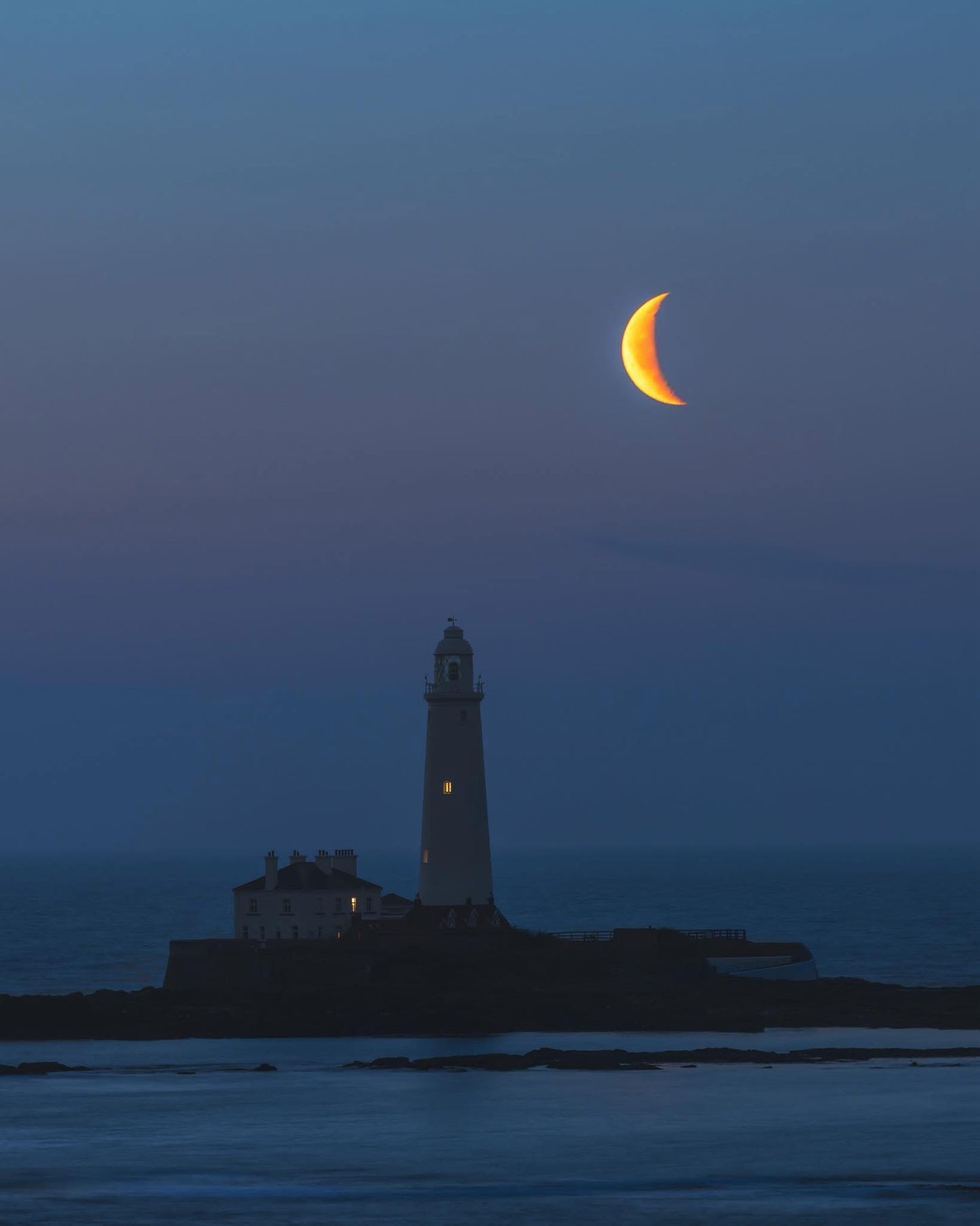 A crescent moon setting over St. Mary’s Lighthouse.