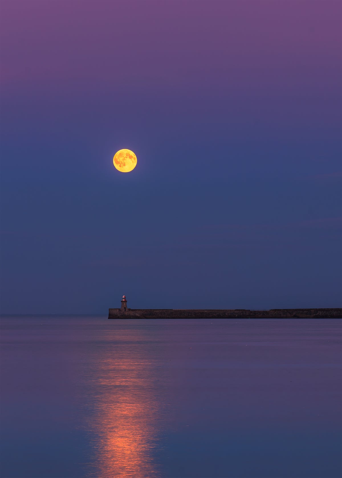 Full moon over South Shields Lighthouse with a pink sky.