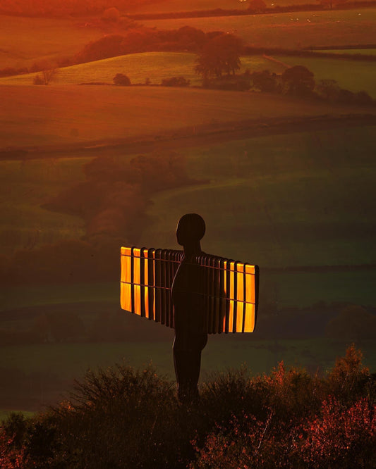 The Angel of the North with its wings lit in golden light.