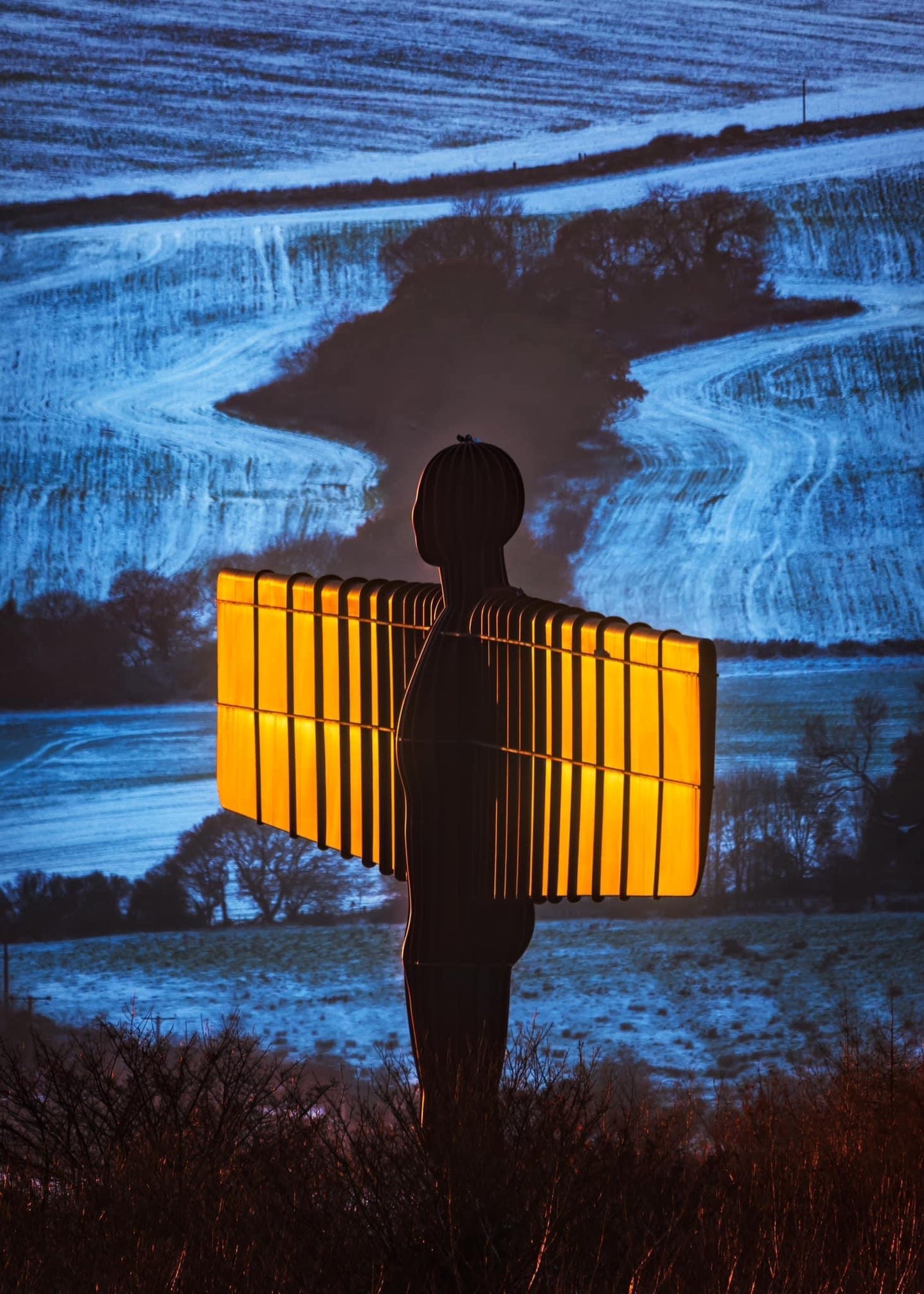 Angel of the North wings lit by the setting sun on a snowy day.