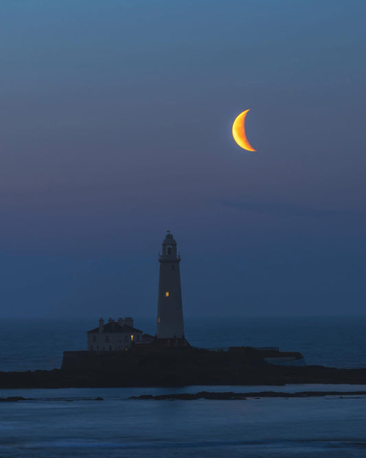 A crescent moon setting over St. Mary’s Lighthouse.