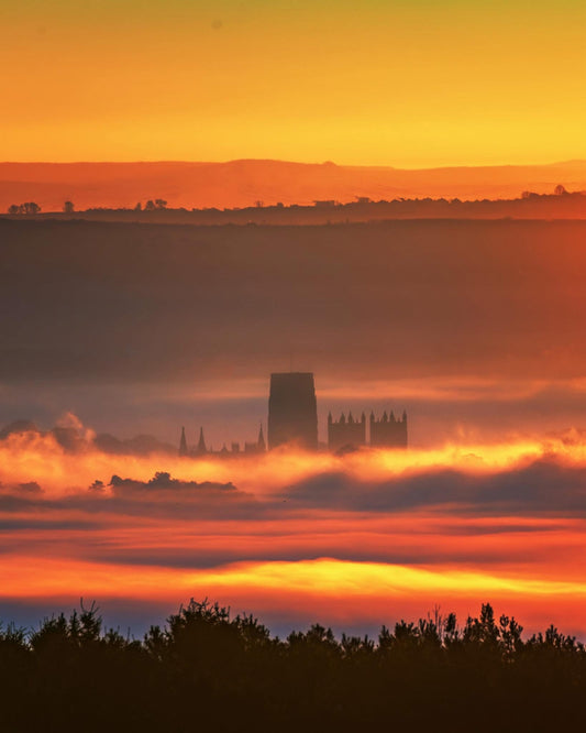 Durham Cathedral buried in the mist lit up by the rising sun.