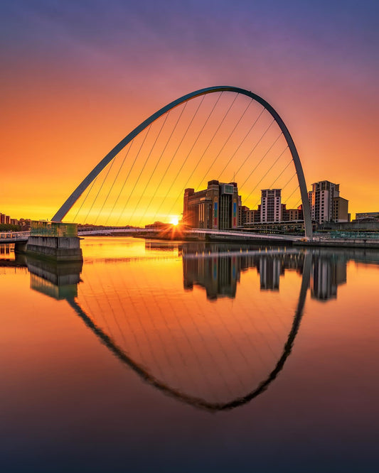 A beautiful glowing sunrise behind a beautiful bridge.