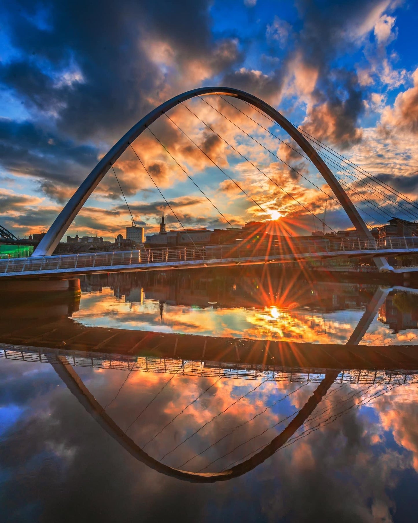 Millennium Bridge with dramatic sky reflections.