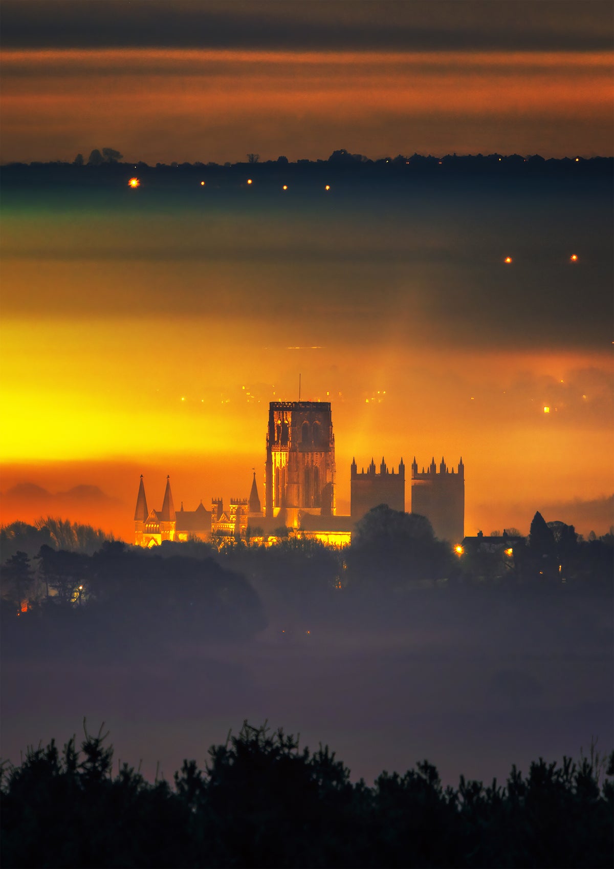A glowing Durham cathedral in the nighttime mist.