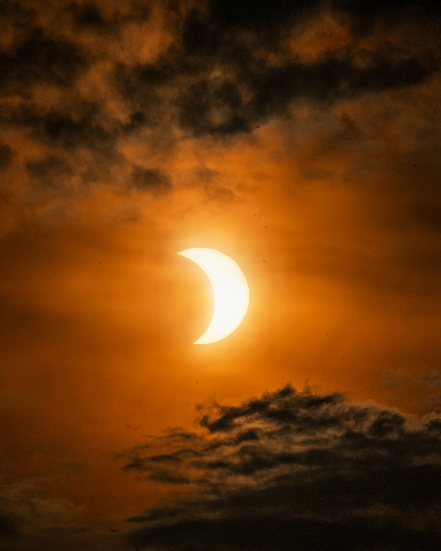 The solar eclipse framed by dramatic clouds.