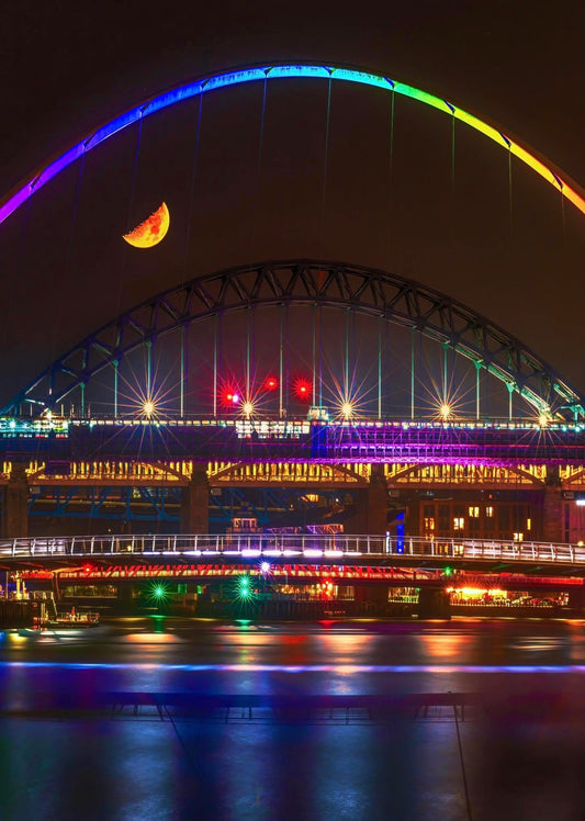 A half moon over a very colourful quayside.