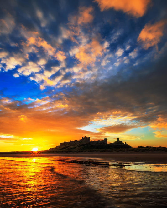 Vibrant sunrise sky at Bamburgh beach.