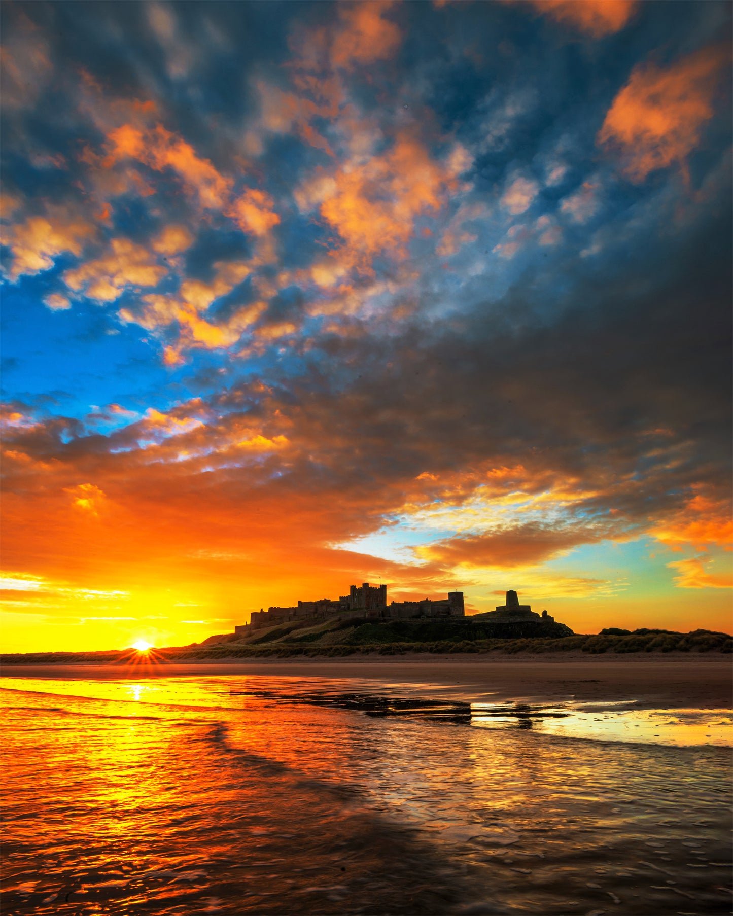 Vibrant sunrise sky at Bamburgh beach.