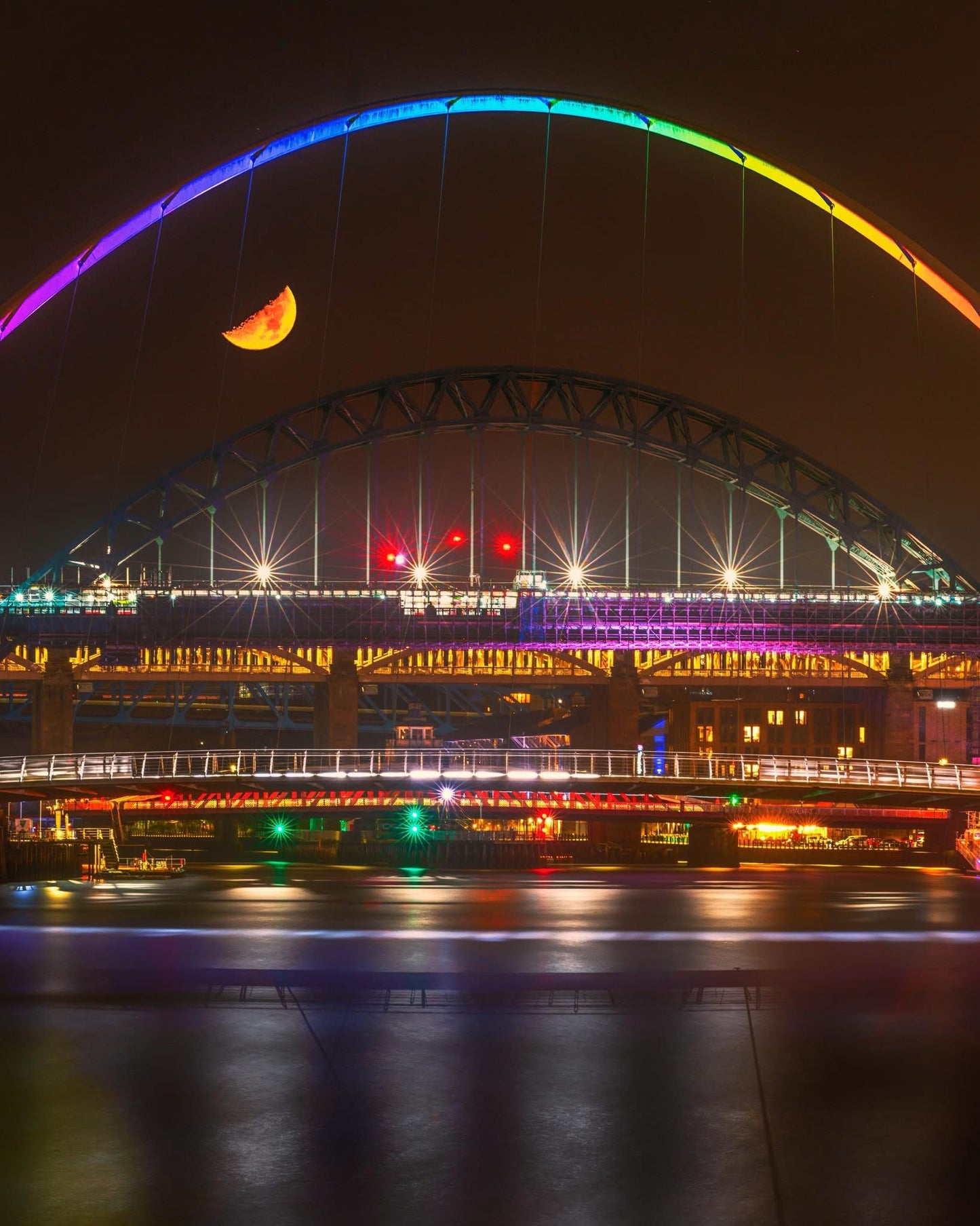 A half moon over a very colourful quayside.