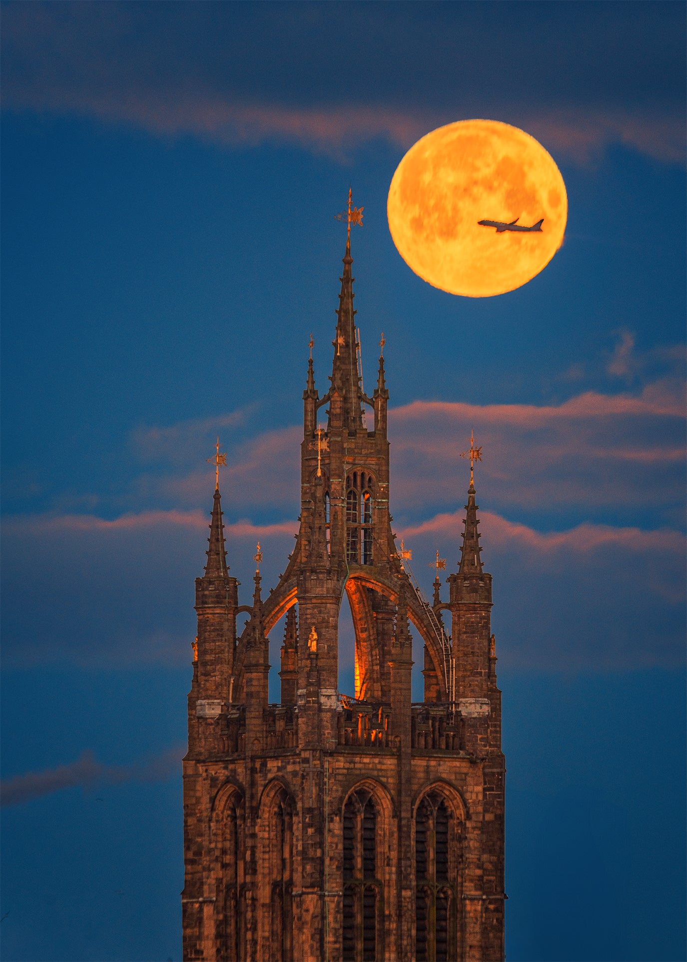 A plane crossing the full moon over Newcastle Cathedral.