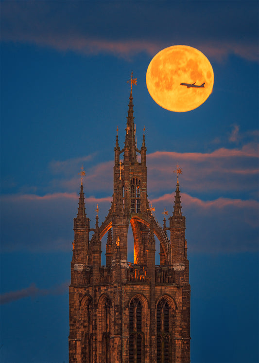 A plane crossing the full moon over Newcastle Cathedral.