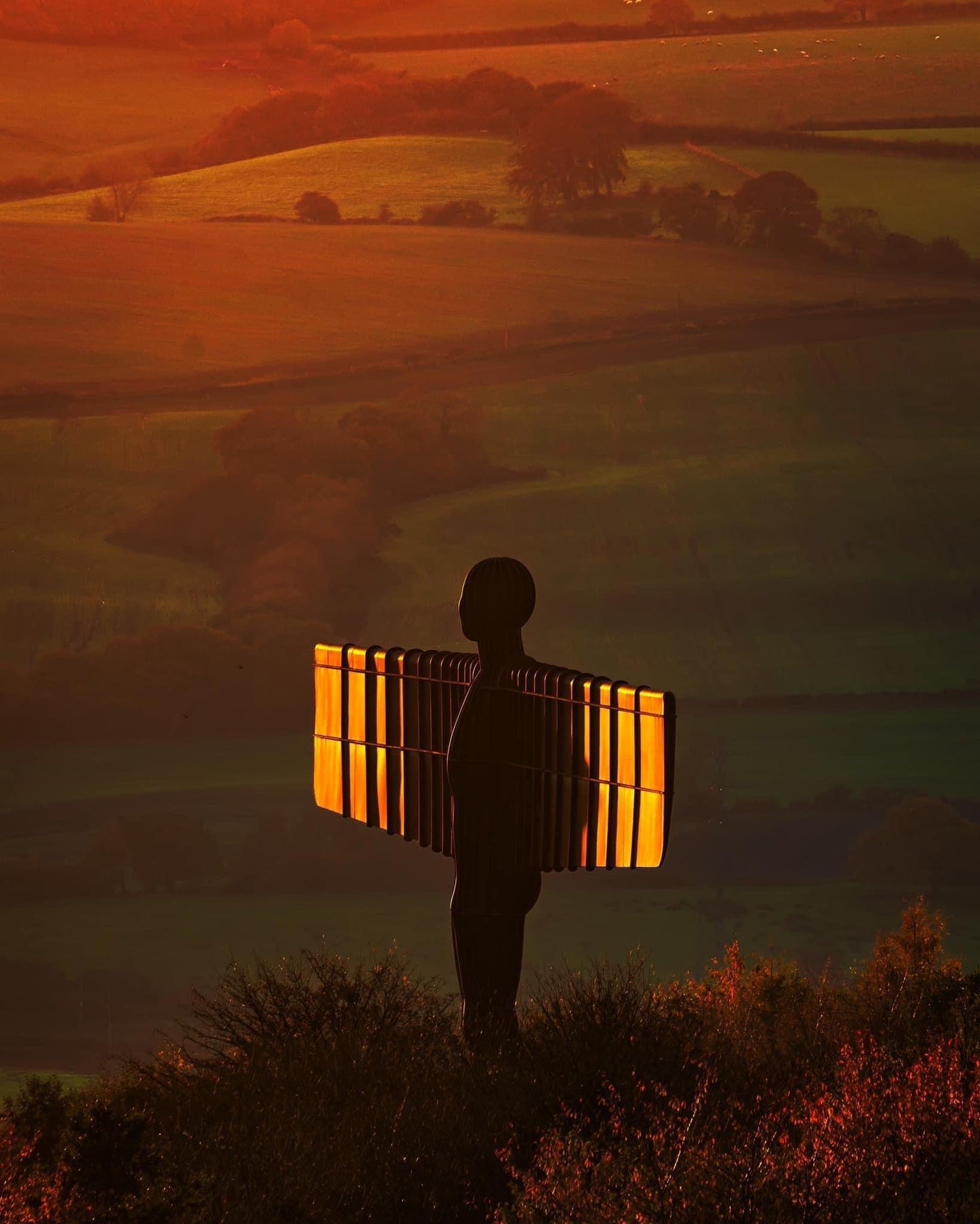 The Angel of the North with its wings lit in golden light.